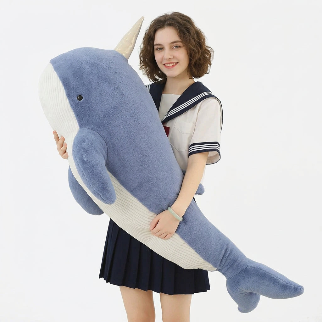 Grande peluche baleine narval bleue avec sa corne, tenue dans les bras