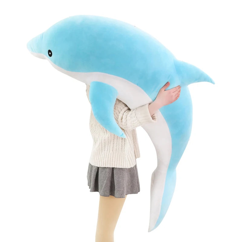 Grande peluche dauphin bleu tenue dans les bras, sur fond blanc