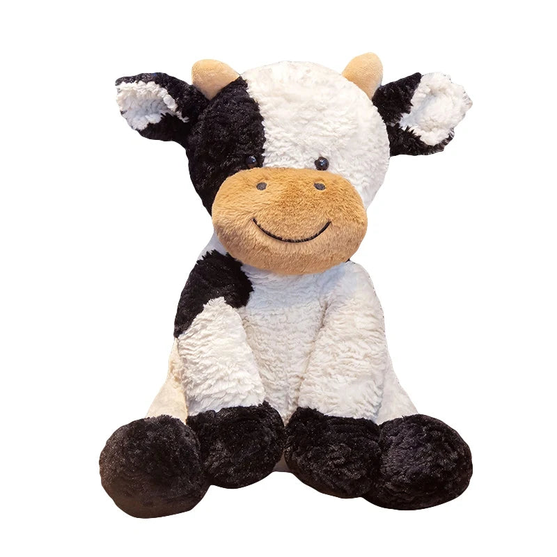 Peluche vache noire et blanche assise, au museau beige souriant, sur fond blanc