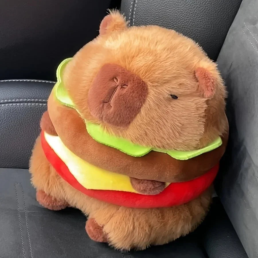Peluche capybara hamburger brune avec salade, fromage et tomate, posée sur un siège en cuir noir